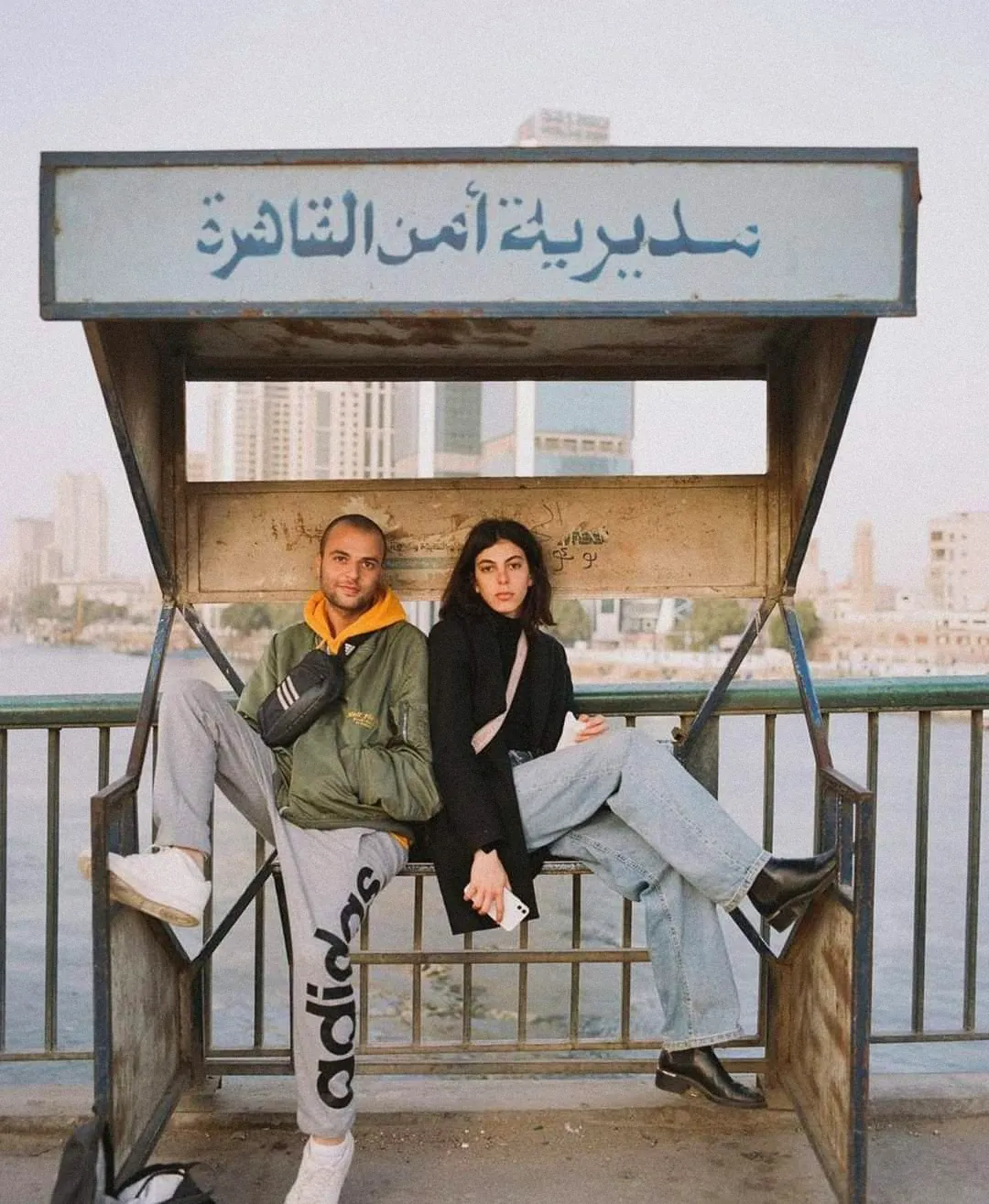 Two young Cairenes on a bench under a Cairo Security Directorate sign
