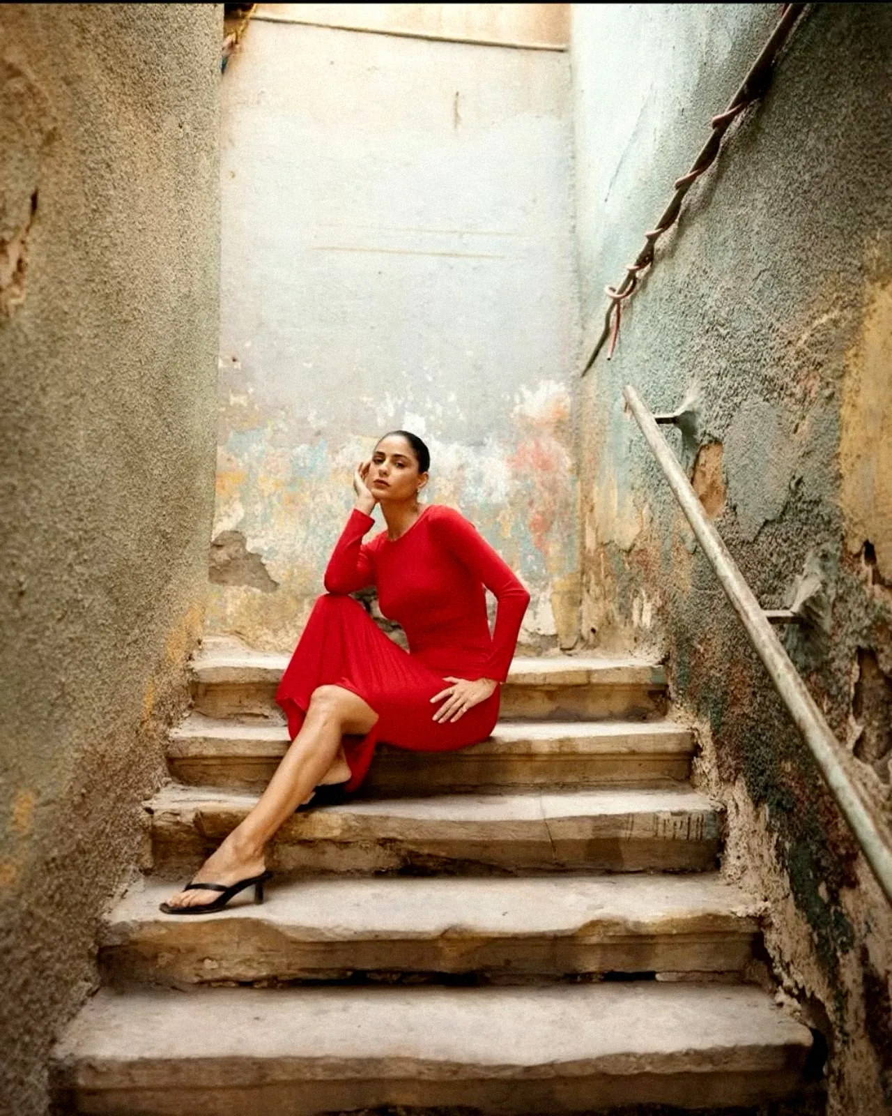 A woman in a red dress on old Cairo stairs, phone to her ear